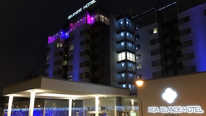 The exterior of Riga Island Hotel with a modern design, featuring a glass facade and illuminated signage. - Riga Islande Hotel with FREE parking (Riga)