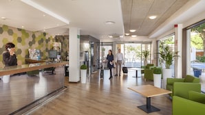 A modern lobby with a reception desk, seating area, and large windows. - Hotel Gala Placidia (Benidorm)