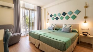 A hotel room with a double bed, a chair, a bedside table with a phone, and a view of the outdoors through a large window. - Hotel Gala Placidia (Benidorm)