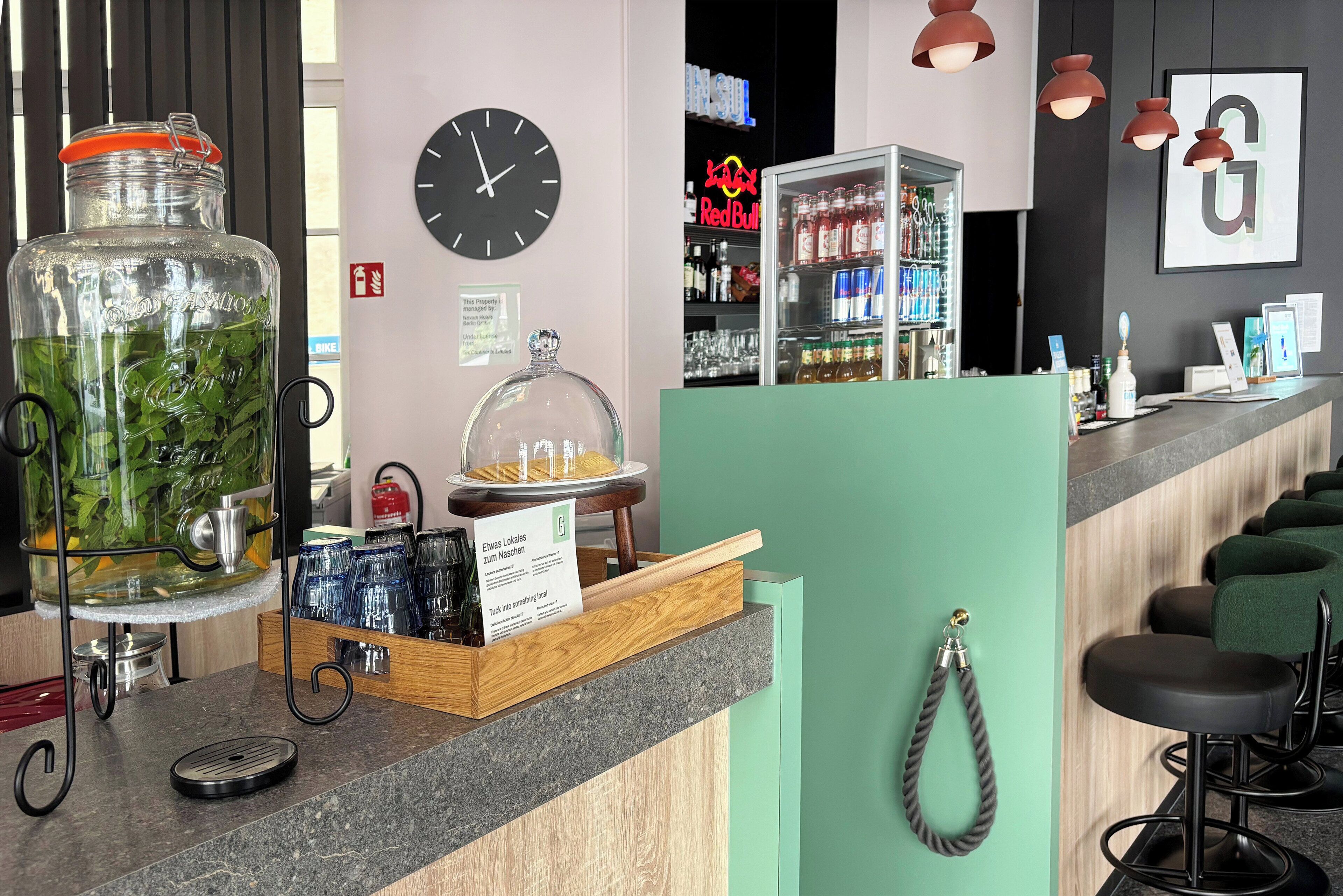 A bar area with a large jar of green herbs, a clock, and a Red Bull sign in the background.