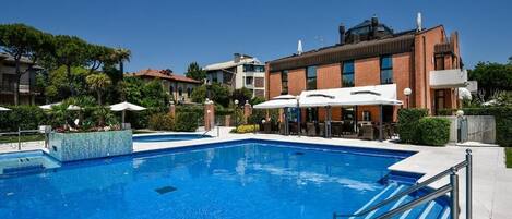 A swimming pool with a blue water feature, surrounded by outdoor seating and a building with a brick facade.