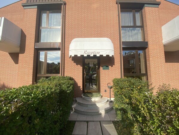 A brick building with a reception area, a small garden, and a water feature. - DB Villas Le Ville del Lido Resort (Venice)