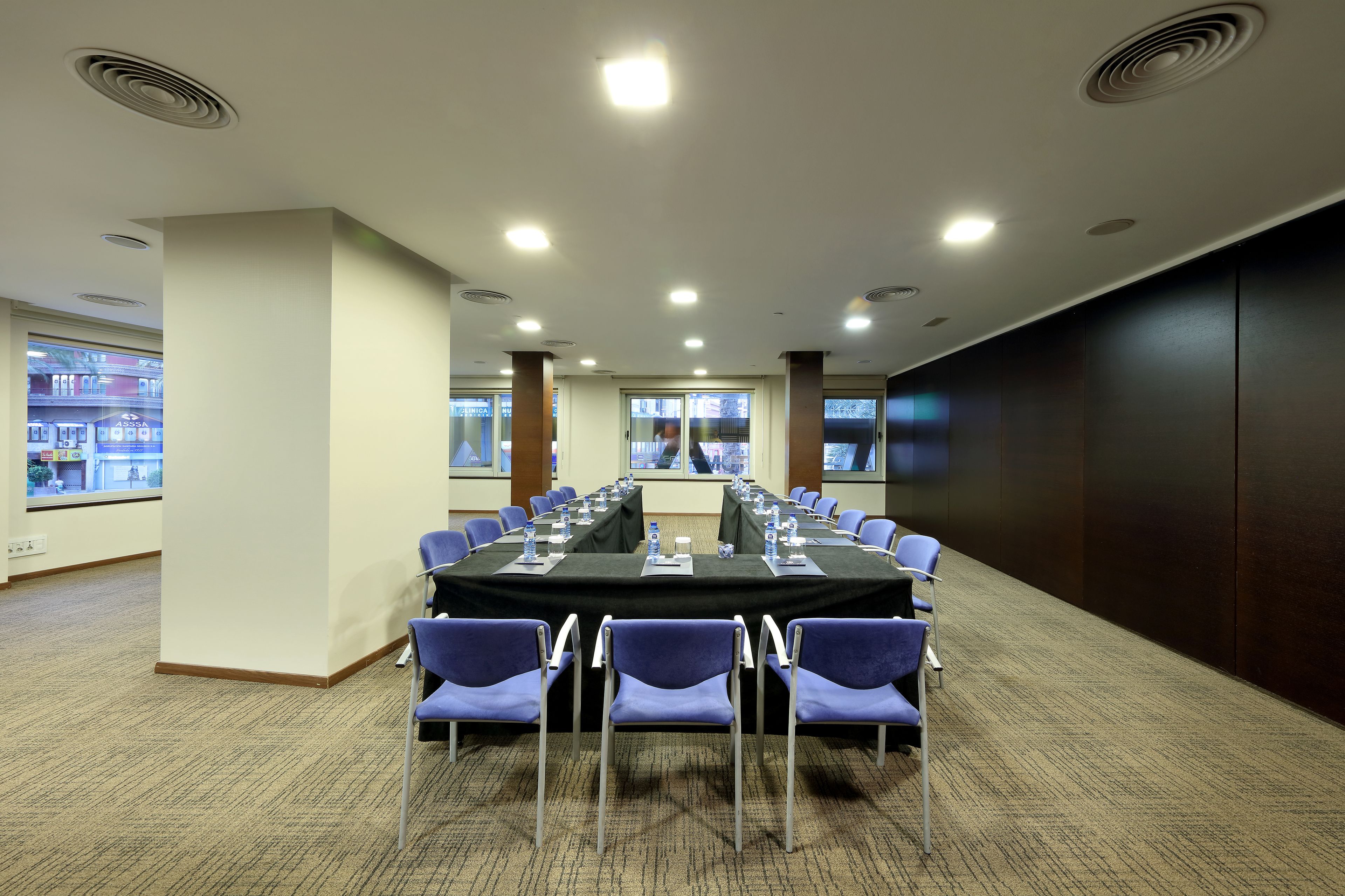 A conference room with a long table, chairs, and a view of the city through large windows.