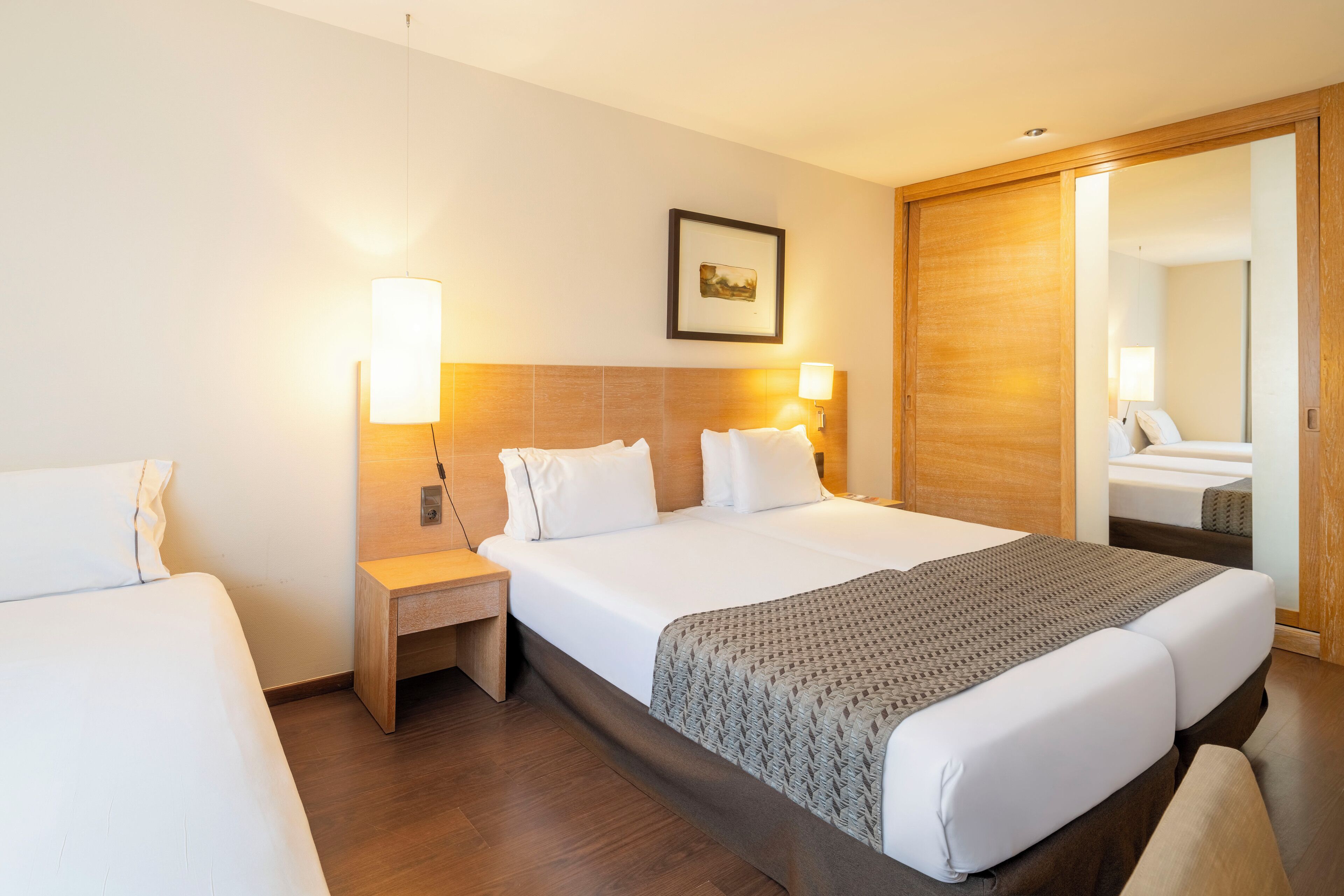 Een hotelkamer met een groot bed, nachtkastjes, een wandlamp en een houten kledingkast.