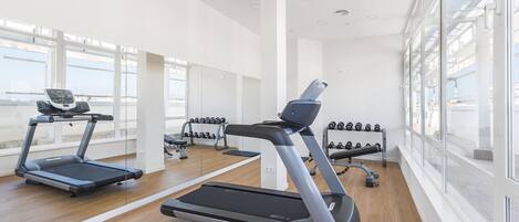 A modern gym with treadmills, dumbbells, and a bench press.
