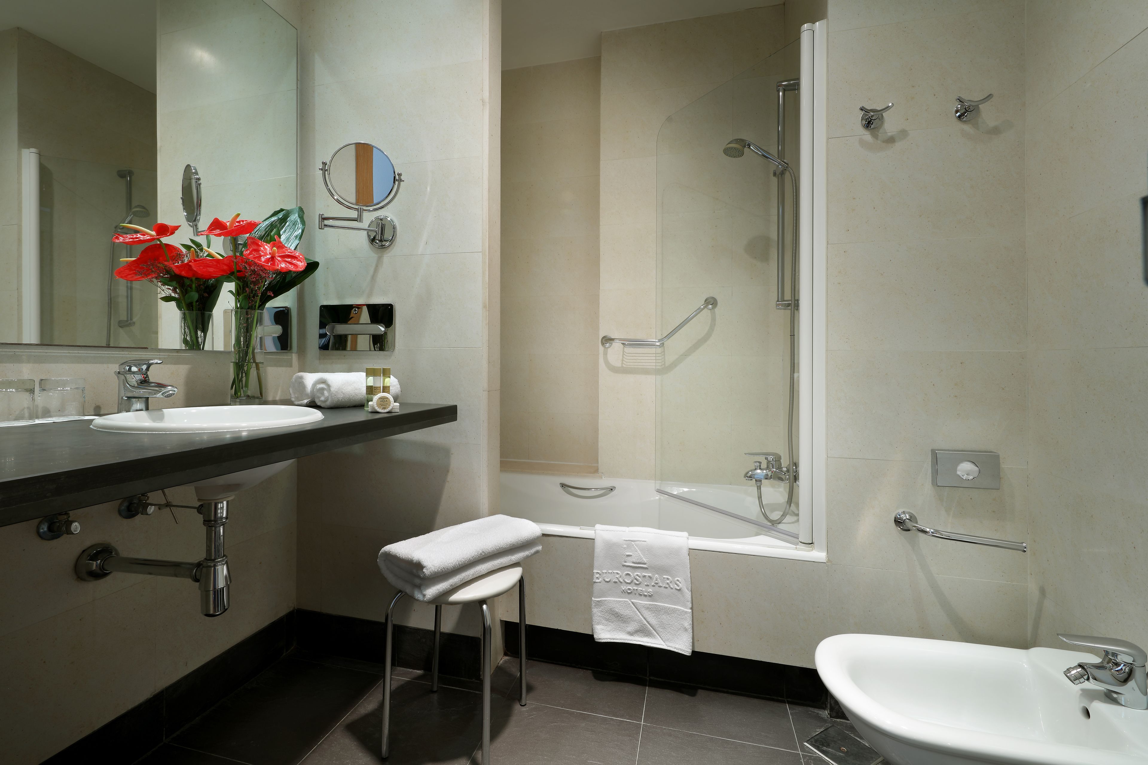 Un baño moderno con lavamanos, espejo y zona de ducha.