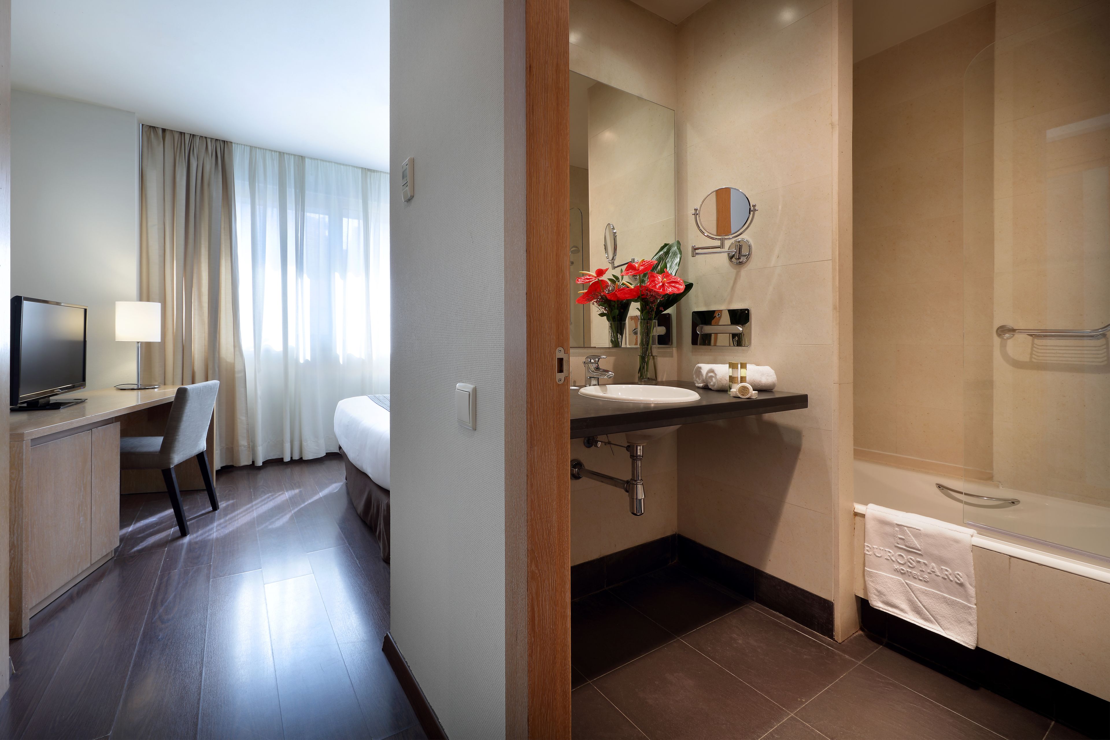 Un baño de hotel con lavamanos, espejo y ducha.