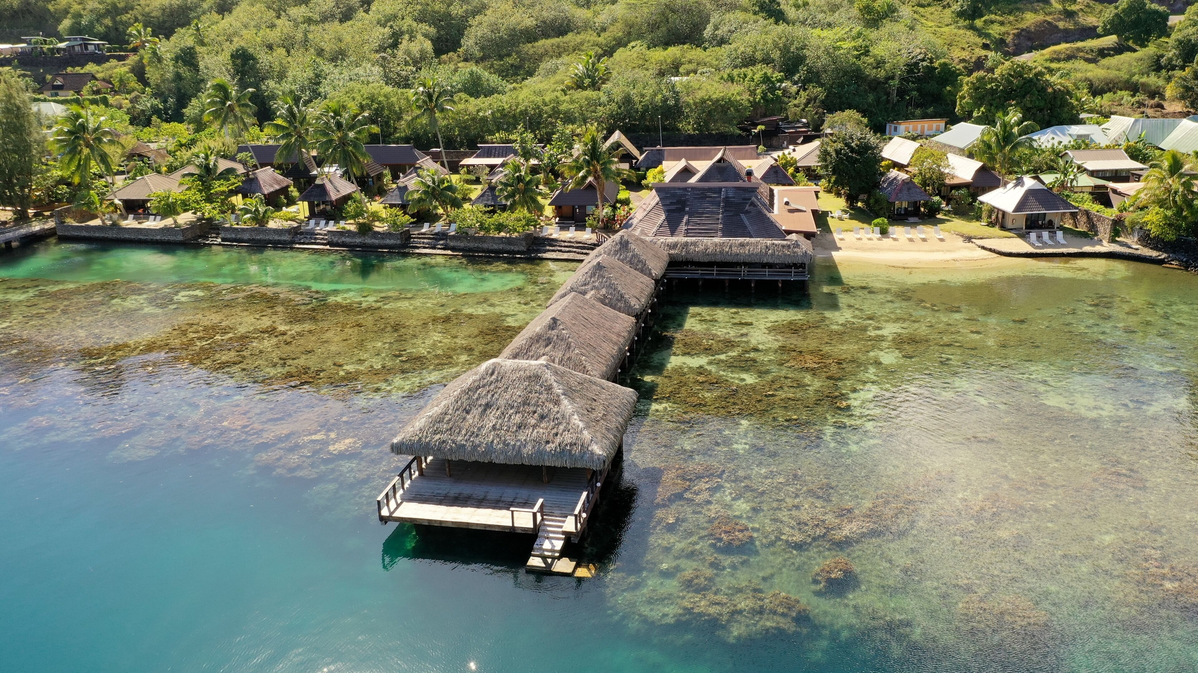 An aerial view of overwater bungalows with clear water and lush greenery.