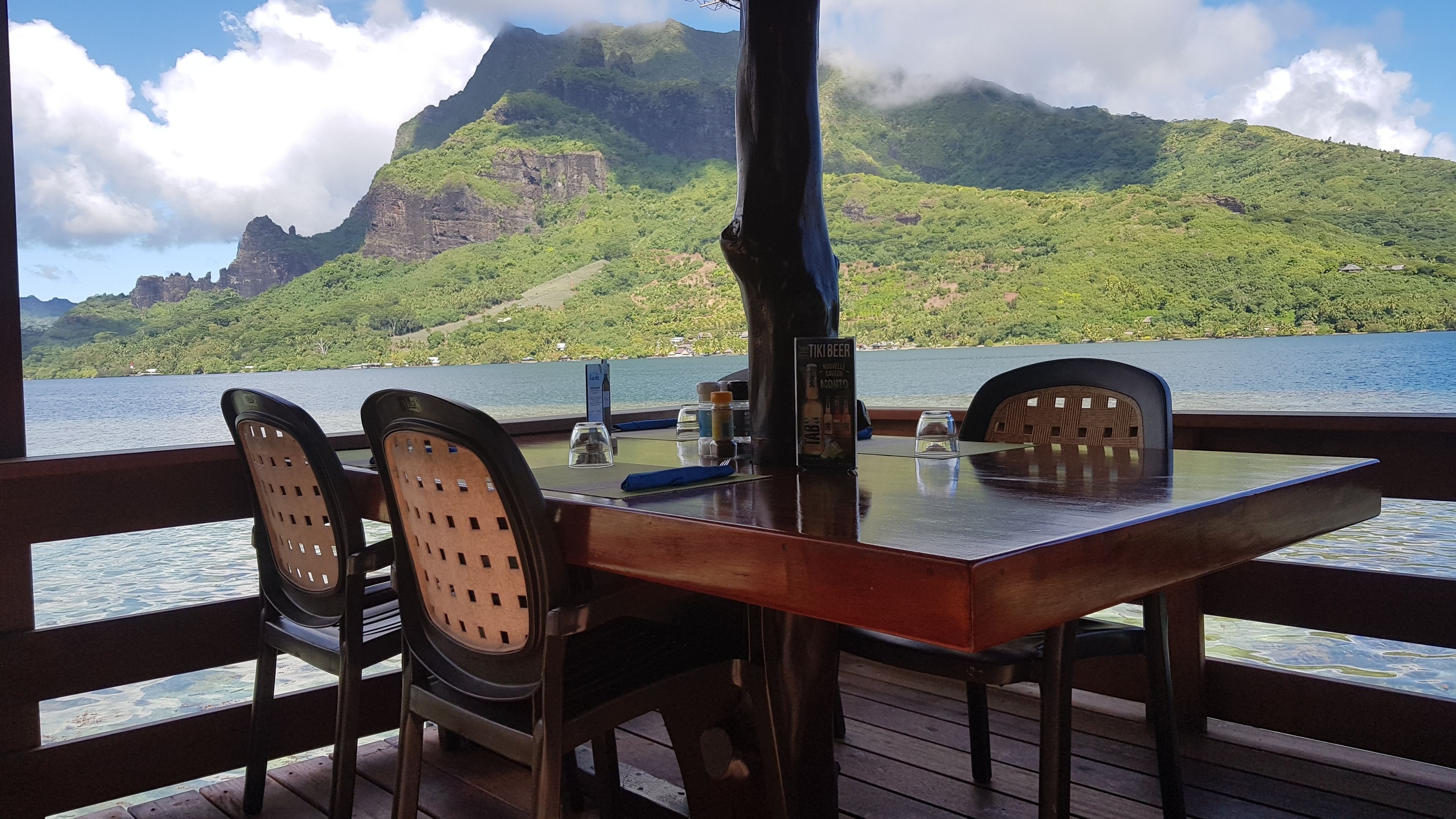 Una mesa con sillas en una terraza con vista a un cuerpo de agua y un paisaje montañoso.