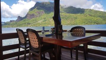 Una mesa con sillas en una terraza con vista a un cuerpo de agua y un paisaje montañoso.