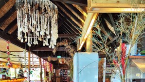A restaurant interior with wooden floors, a long counter with a coffee menu, and hanging decorations. - Hotel Kaveka (Moorea-Maiao)