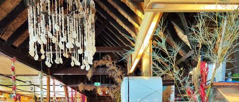 Interior de restaurante con pisos de madera, una barra larga con menú de café y adornos colgantes.