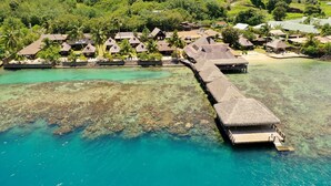 An aerial view of a resort with overwater bungalows connected by a wooden walkway. - Hotel Kaveka (Moorea-Maiao)