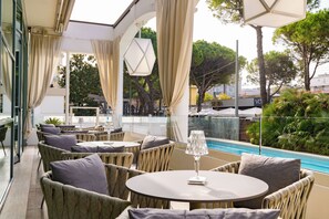 An outdoor seating area with wicker furniture, a pool, and a view of the surrounding greenery. - Hotel Continental Rimini (Rimini)