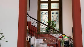 A staircase with a wrought iron railing, a stained glass window, and a potted plant. - Hotel Tonic (Palermo)