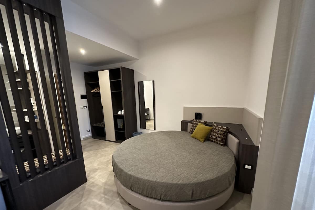 Un dormitorio moderno con una cama redonda, un armario y un espejo.