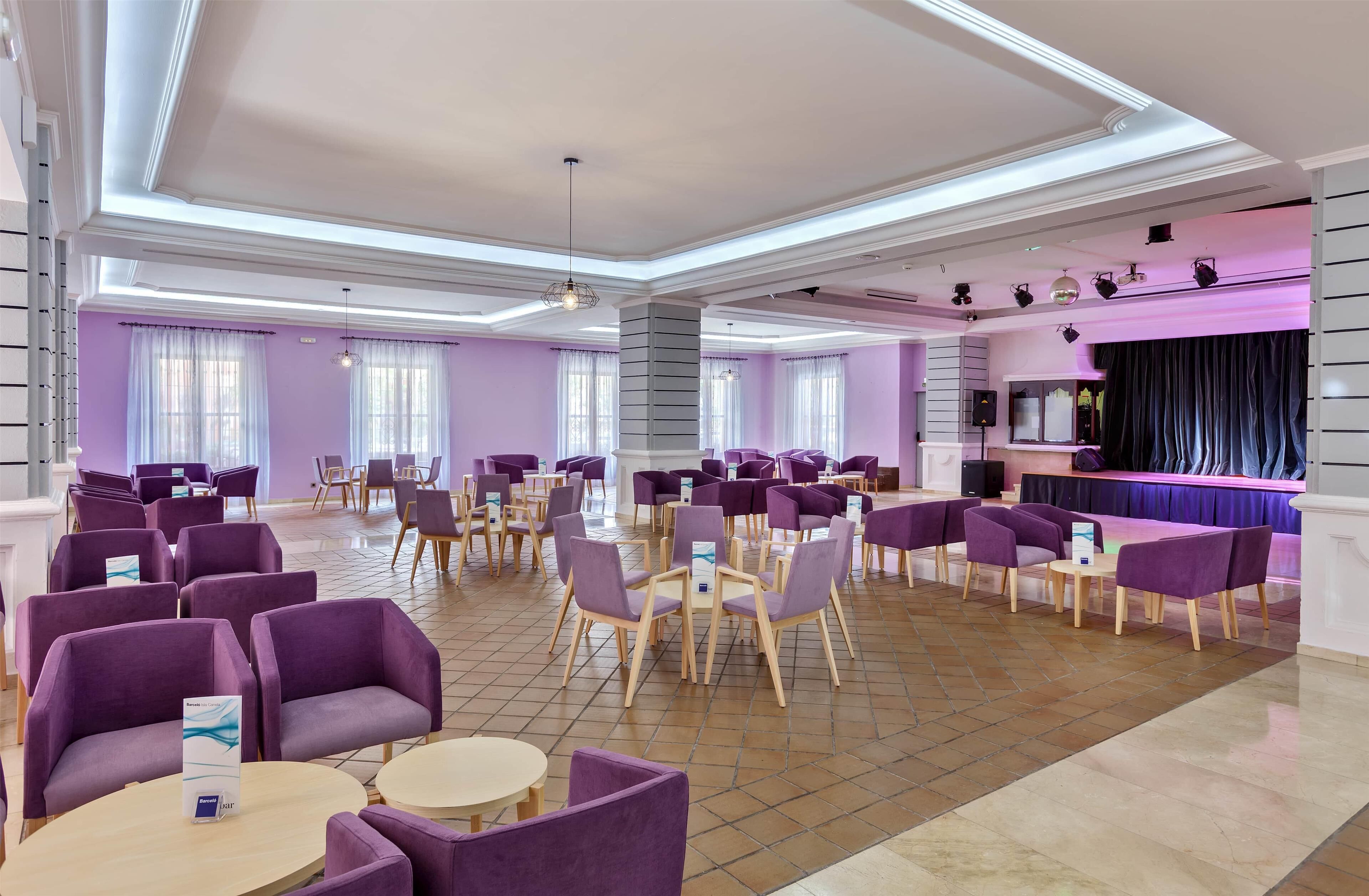 A spacious lobby with purple seating, a stage, and a modern ceiling design.