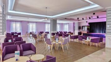 A spacious lobby with purple seating, a stage, and a modern ceiling design.
