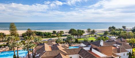 A coastal resort with a swimming pool, beach, and palm trees.