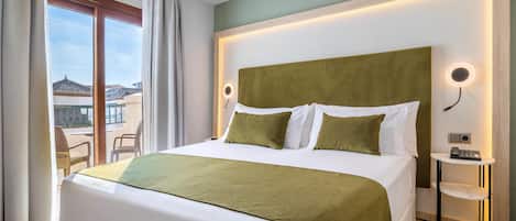 A hotel room with a large bed, a bedside table with a lamp, and a view of the outside.