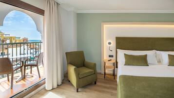 Quarto de hotel com varanda, cama com roupa de cama verde e vista para o mar.