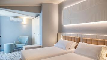 Une chambre d’hôtel moderne dotée d’un grand lit, d’un coin salon avec un fauteuil et d’un climatiseur fixé au mur.