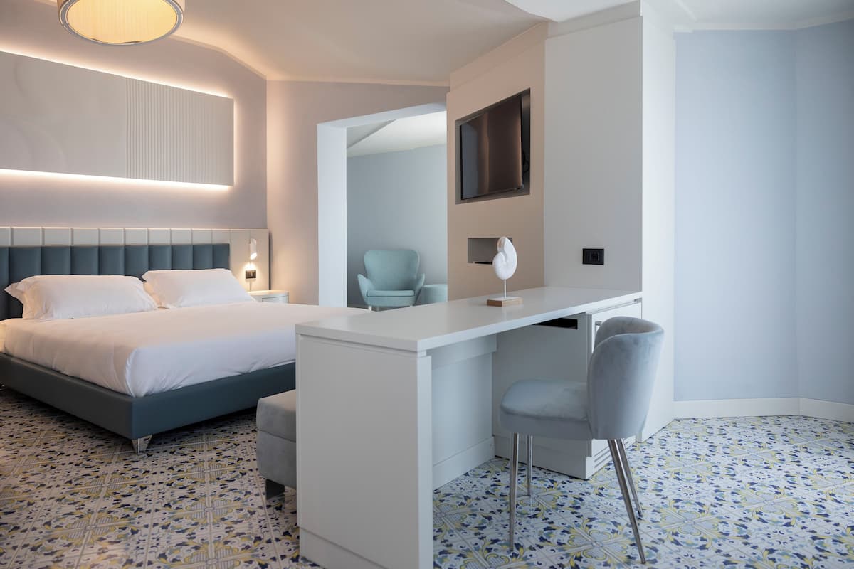 A modern hotel room with a bed, a desk, and a chair.