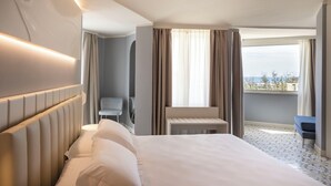 A hotel room with a large bed, a small table, a chair, and a view of the outdoors. - Grand Hotel (Forte dei Marmi)