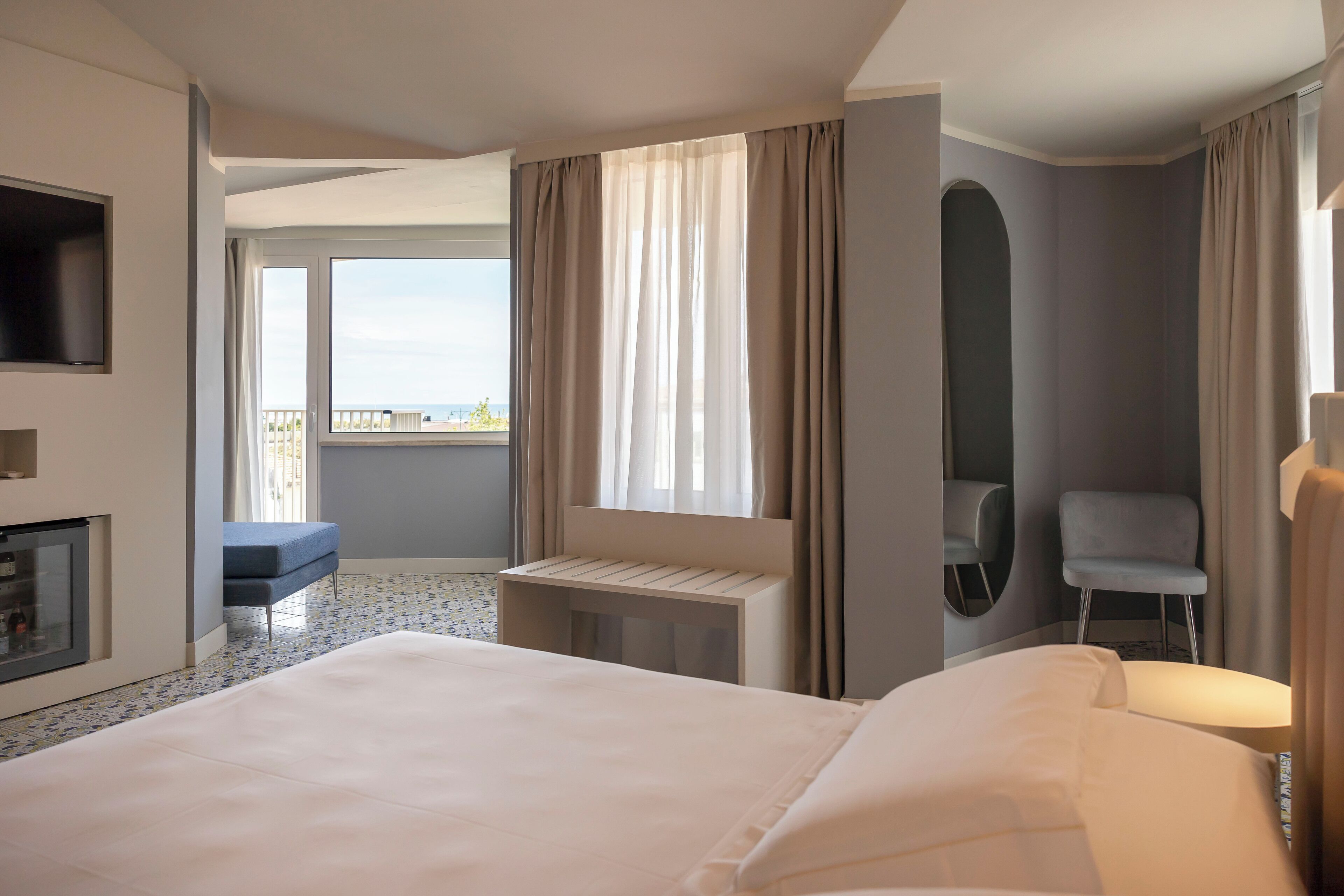 Een hotelkamer met een groot bed, een klein bureau, een stoel, een televisie en een balkon met uitzicht.