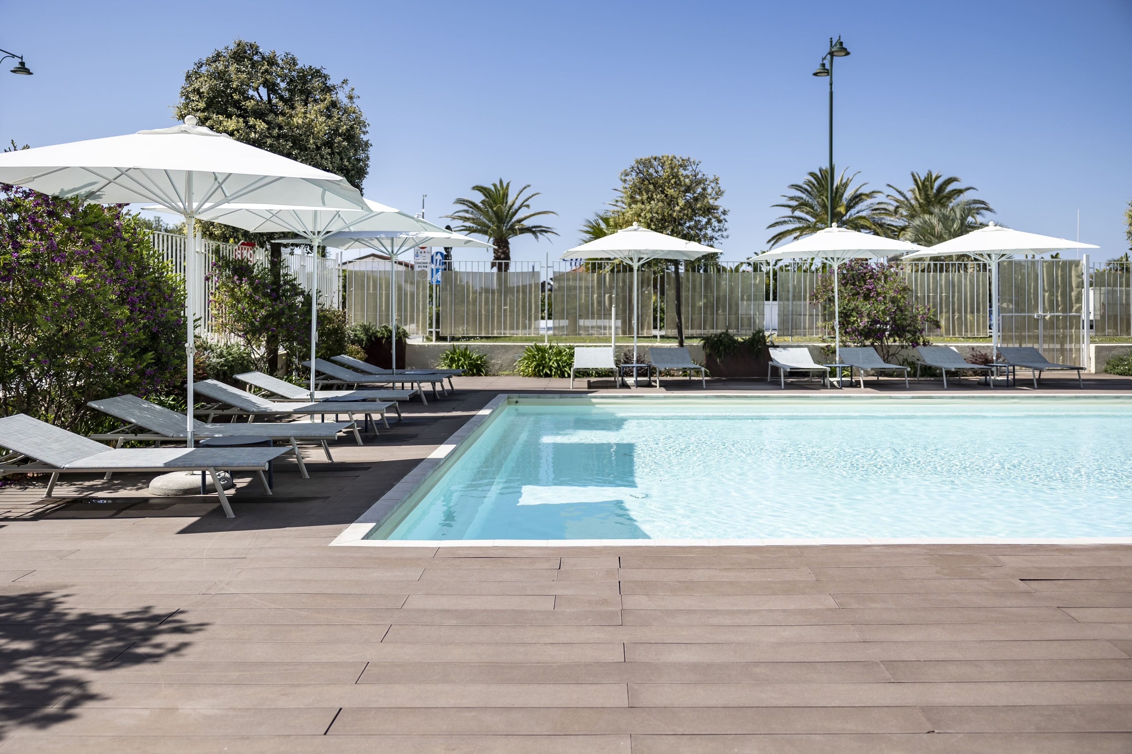 Una piscina al aire libre, sombrillas, tumbonas
