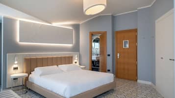 Una camera d'albergo moderna con un letto grande, comodini, uno specchio e una porta in legno.