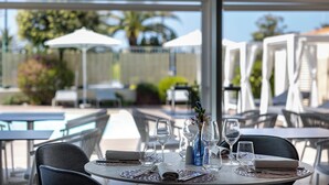 A restaurant with outdoor seating, tables, chairs, umbrellas, and a pool in the background. - Grand Hotel (Forte dei Marmi)