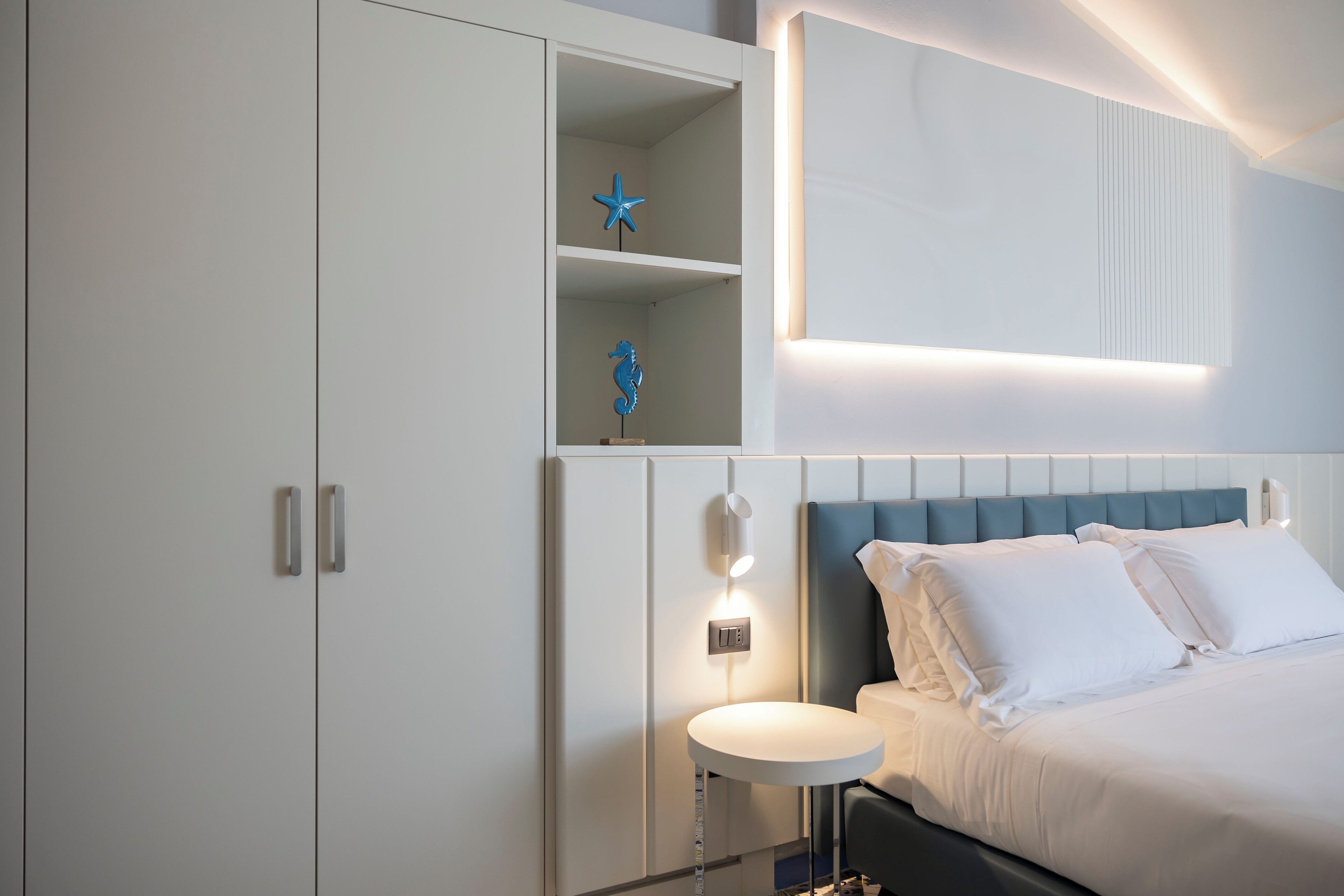 A modern bedroom with a bed, bedside table, and a built-in shelf with decorative items.