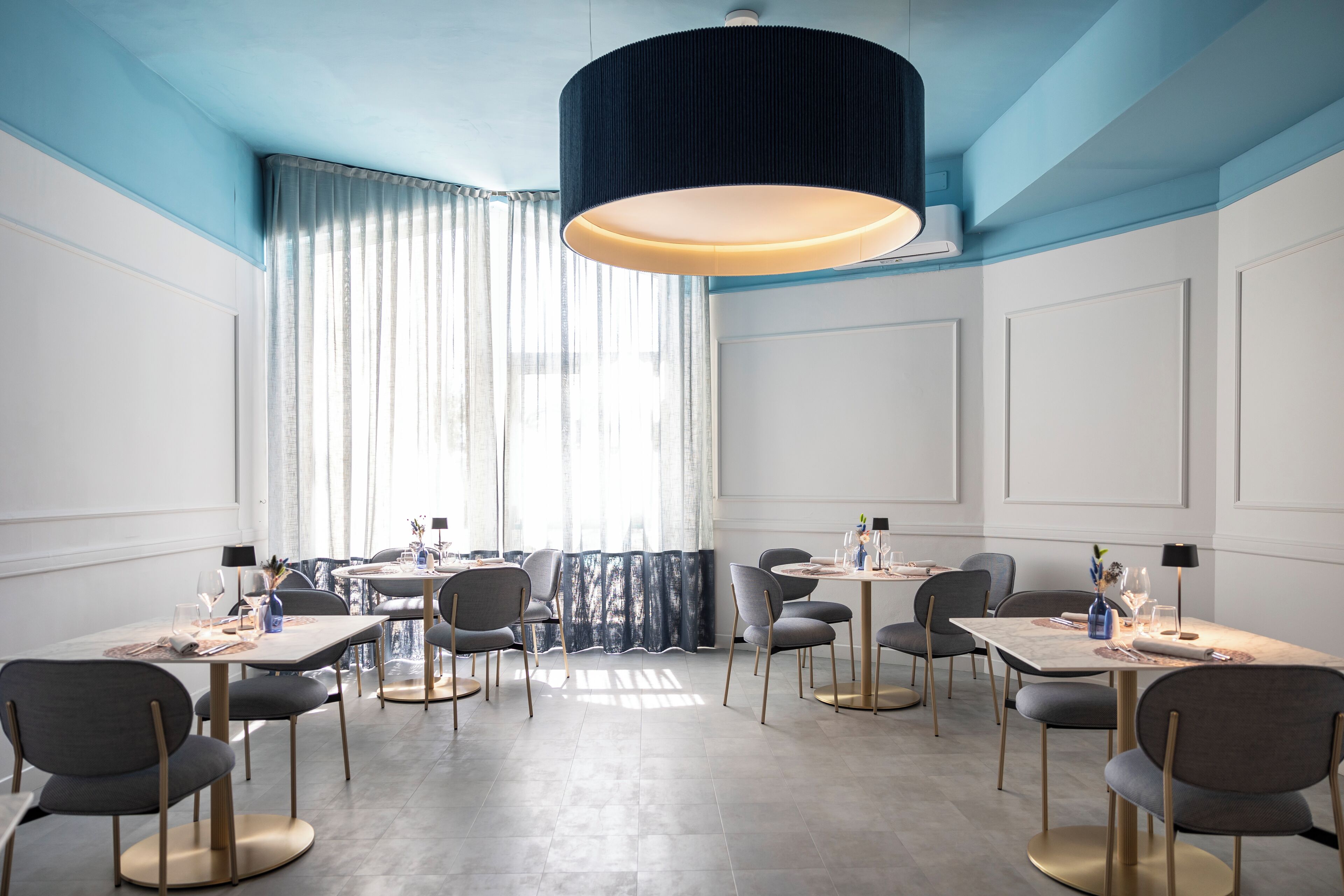 Un comedor moderno con una mesa grande, sillas y una lámpara colgante.