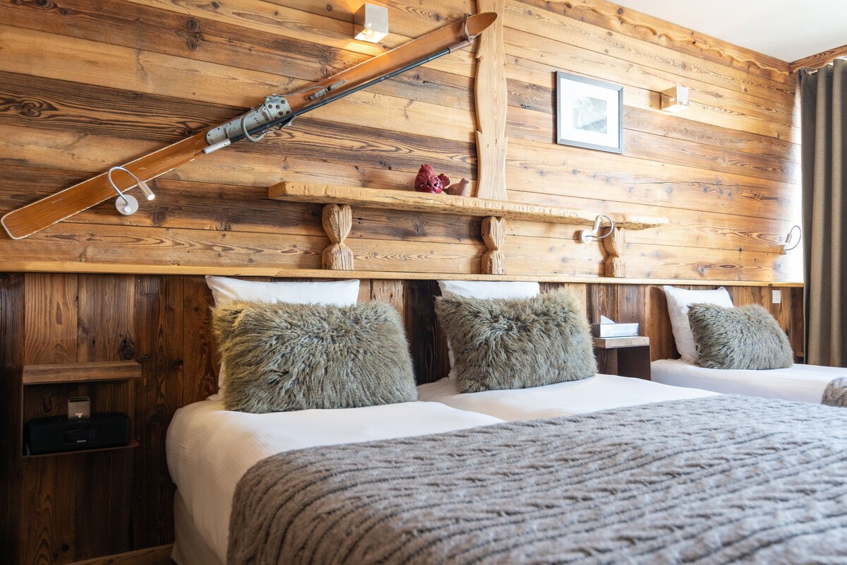 Une pièce aménagée comme un chalet en bois, avec un lit, deux oreillers, une étagère avec un tableau et un bâton de ski.