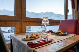 A wooden table with a glass of water, a red napkin, and plates of food.