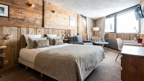 Una habitación de hotel moderna con una cama grande, un sofá, un escritorio y una ventana con vista a la ciudad.
