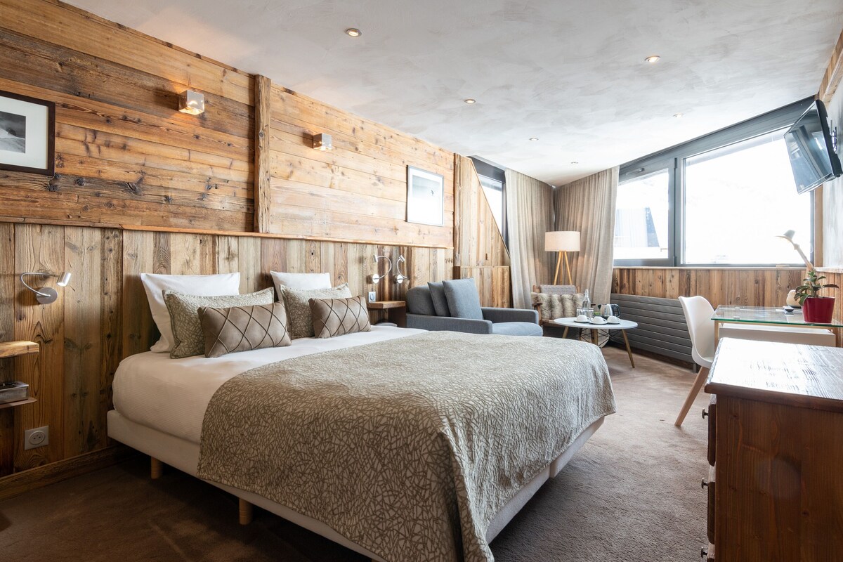 Une chambre d’hôtel moderne, dotée d’un grand lit, d’un canapé, d’un bureau et d’une fenêtre donnant sur la ville.