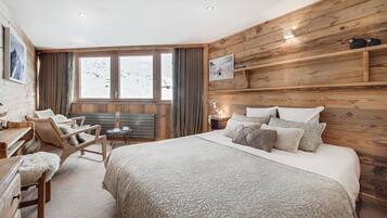 Un cuarto acogedor de madera con una cama grande, un escritorio de madera y una silla.