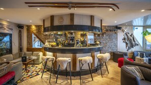 Un área de bar moderna con pared de piedra, detalles de madera y un techo alto.