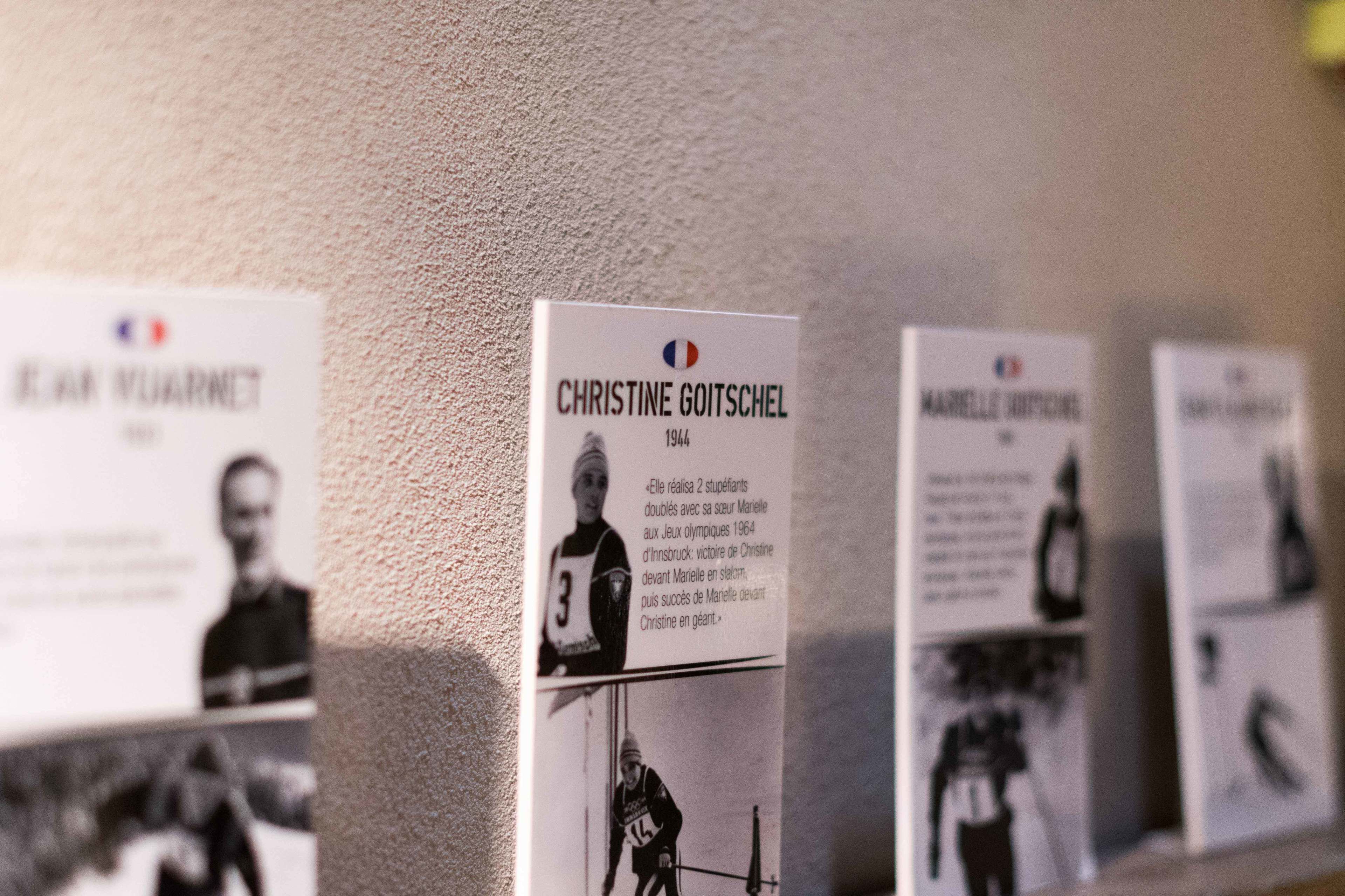 A wall with several informational signs, including one for Christine Goitschel, a 1944 Olympic athlete.