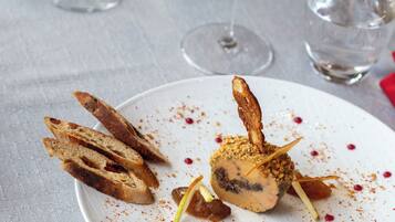 A dining table with a white plate of food, two wine glasses, and a water glass.