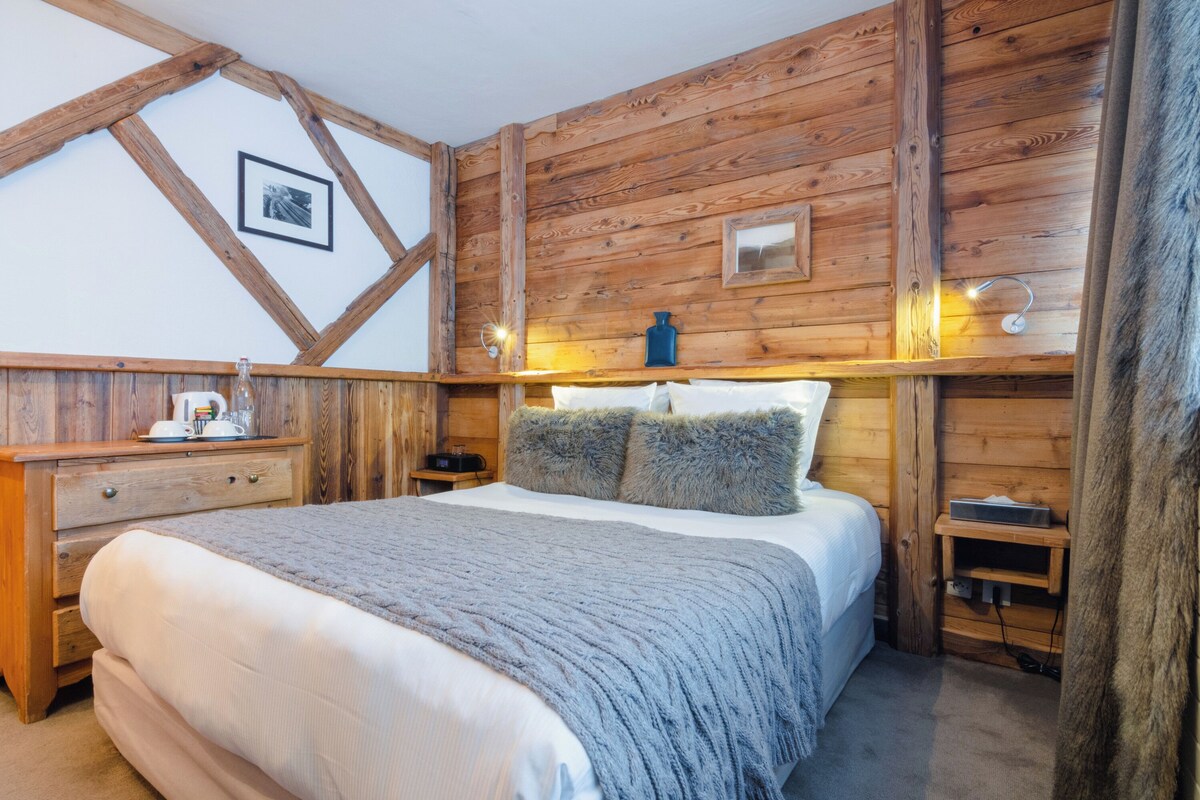 Une chambre de style cabane en bois, avec un lit, des tables de chevet et une commode.