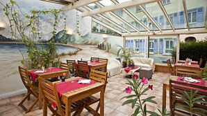 Un restaurante con mesas y sillas de madera, manteles rojos y un mural de un paisaje pintoresco.