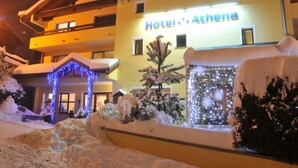 Un hotel con un cartel que dice 'Hotel Athéna' y adornos de nieve alrededor de la entrada.