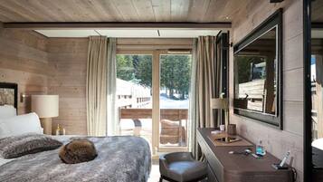 Une chambre d’hôtel avec un intérieur en bois, un lit recouvert d’une couverture moelleuse, un bureau avec un miroir et une vue sur l’extérieur.