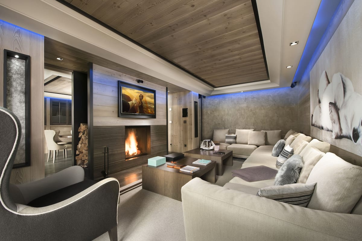 A modern living room with a fireplace, comfortable seating, and a large TV mounted on the wall.