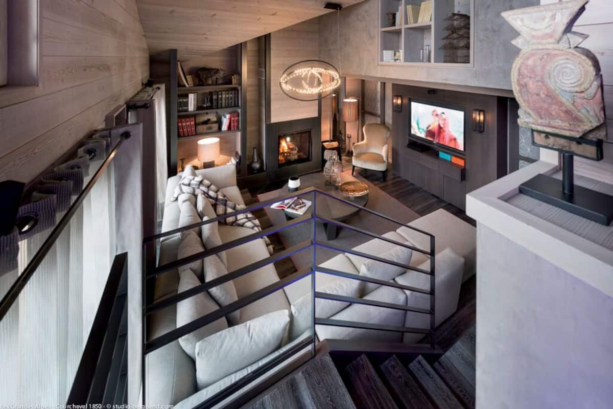 A modern living room with a fireplace, a television, and a staircase leading to an upper level.