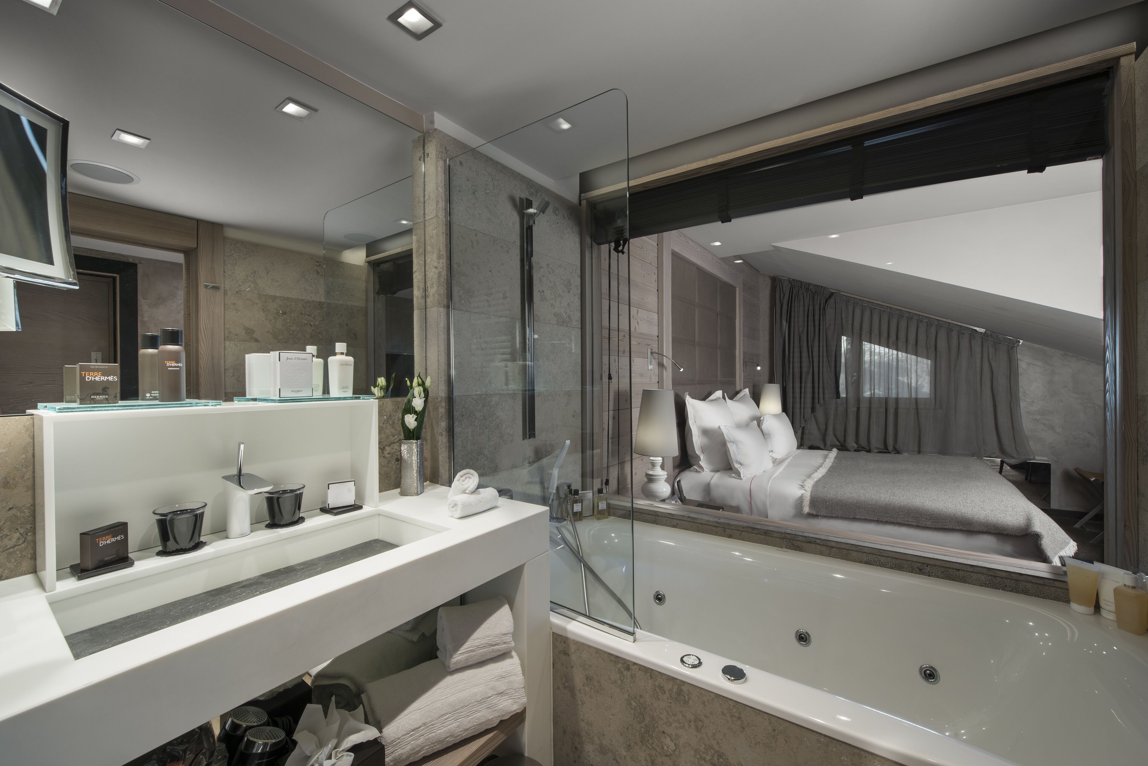 Une salle de bain moderne avec une douche à parois de verre, une grande baignoire et un meuble-lavabo avec des articles de toilette.