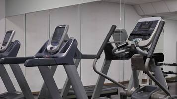 Tres máquinas de ejercicio en un gimnasio con un espejo grande.